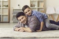 Portrait of happy smiling young father and his little son lying on floor at home Royalty Free Stock Photo