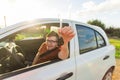 Portrait of happy smiling young man, buyer sitting in his new car and showing keys outside dealer office. Personal Royalty Free Stock Photo