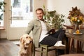 Portrait of happy smiling young man, cafe visitor, sitting in coffee shop with his dog, petting golden retriever Royalty Free Stock Photo