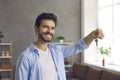 Portrait of happy smiling young man showing us keys to his new house or apartment Royalty Free Stock Photo