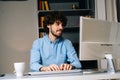 Portrait of happy smiling young man using computer and typing online message on wireless keyboard . Royalty Free Stock Photo