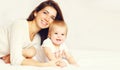 Portrait of happy smiling young mother and cute baby lying on the bed at home together Royalty Free Stock Photo