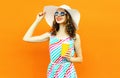 Portrait happy smiling young woman with cup of fruit juice in summer straw hat, colorful striped dress on orange wall Royalty Free Stock Photo