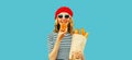 Portrait of happy smiling young woman eating croissant holding shopping paper grocery bag with long white loaf bread baguette