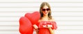 Portrait of happy smiling young woman with gift box and bunch of red heart shaped balloons on white background Royalty Free Stock Photo
