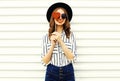 Portrait happy smiling young woman hiding her eye with red heart shaped lollipop in black round hat, white striped shirt on white Royalty Free Stock Photo