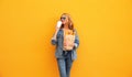 Portrait of happy smiling young woman holding grocery shopping paper bag with long white bread baguette and cup of coffee on Royalty Free Stock Photo