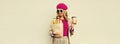 Portrait of happy smiling young woman holding grocery shopping paper bag with long white bread baguette and cup of coffee on gray Royalty Free Stock Photo