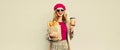 Portrait of happy smiling young woman holding grocery shopping paper bag with long white bread baguette and cup of coffee on gray Royalty Free Stock Photo