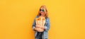 Portrait of happy smiling young woman holding grocery shopping paper bag with long white bread baguette on orange background Royalty Free Stock Photo