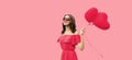 Portrait of happy smiling young woman holding pink heart shaped balloon on studio background Royalty Free Stock Photo