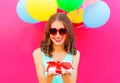 Portrait happy smiling young woman holds in hands a gift box over an air colorful balloons a pink background Royalty Free Stock Photo