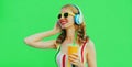 Portrait happy smiling young woman listening to music in headphones with fresh cup of juice on green background Royalty Free Stock Photo