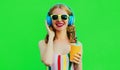 Portrait happy smiling young woman listening to music in headphones with fresh cup of juice on green background Royalty Free Stock Photo