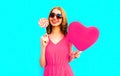 Portrait happy smiling young woman with lollipop, pink heart shaped air balloons on colorful blue Royalty Free Stock Photo