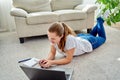 Portrait of happy smiling young woman lying on floor with laptop and using mobile phone at home, copy space. Royalty Free Stock Photo