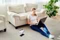 Portrait of happy smiling young woman lying on floor and using laptop at home, copy space. Royalty Free Stock Photo