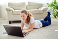 Portrait of happy smiling young woman lying on floor and using laptop at home, copy space. Royalty Free Stock Photo