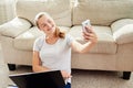 Portrait of happy smiling young woman lying on floor, using laptop and making selfie at home, copy space. Royalty Free Stock Photo