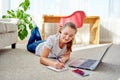 Portrait of happy smiling young woman lying on floor, using laptop and working at home, copy space. Royalty Free Stock Photo