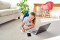 Portrait of happy smiling young woman lying on floor, using laptop and working at home, copy space. Royalty Free Stock Photo