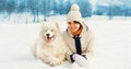 Portrait of happy smiling young woman owner with her white Samoyed dog in winter park Royalty Free Stock Photo