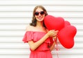 Portrait happy smiling young woman in red dress and sunglasses with air balloons heart shape over white Royalty Free Stock Photo