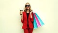 Portrait happy smiling young woman with shopping bags and coffee cup wearing a red business blazer on a background Royalty Free Stock Photo