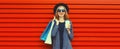 Portrait of happy smiling young woman with shopping bags and cup of coffee wearing blazer, black round hat on red background, Royalty Free Stock Photo