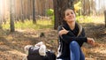 Portrait of happy smiling young woman sitting on ground and leaning on pine tree in forest Royalty Free Stock Photo