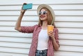 Portrait happy smiling young woman taking selfie picture by smartphone with cup of orange juice wearing summer round straw hat Royalty Free Stock Photo