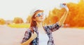 Portrait of happy smiling young woman taking selfie by smartphone wearing summer straw hat, backpack in summer park Royalty Free Stock Photo