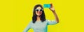 Portrait of happy smiling young woman taking selfie with smartphone wearing summer straw round hat on yellow background Royalty Free Stock Photo