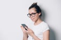 Portrait of happy smiling young woman wearing glasses using smartphone on white background