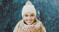 Portrait of happy smiling young woman wearing knitted hat and scarf in winter over a snowflakes background Royalty Free Stock Photo