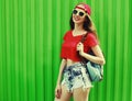 Portrait happy smiling young woman wearing a shorts, red baseball cap and backpack in a city Royalty Free Stock Photo