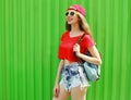 Portrait happy smiling young woman wearing a shorts, red baseball cap and backpack in a city Royalty Free Stock Photo