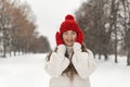 Portrait of happy smiling young woman in white wool sweater, red hat and mittens in winter park. Woman in warm clothes Royalty Free Stock Photo