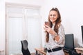 Casual young woman texting on phone in her office Royalty Free Stock Photo
