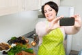 Portrait of housewife in apron making selfie in domestic kitchen Royalty Free Stock Photo