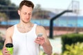 Portrait of a happy sports man standing near sport field with a mobile phone outdoors Royalty Free Stock Photo