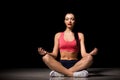 Portrait of happy sporty woman relaxing in lotus position. Joyful female model breathing fresh air indoors. Healthy Royalty Free Stock Photo