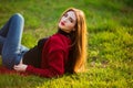 Portrait of happy sporty woman relaxing in park on green meadow. Joyful female model breathing fresh air outdoors Royalty Free Stock Photo