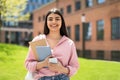 Portrait of happy student girl with cellphone and workbooks walking in college campus and smiling at camera Royalty Free Stock Photo