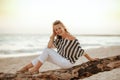 Traveller woman sitting on wooden snag on seashore in evening