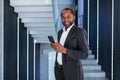 Portrait of happy successful African American boss, man smiling and looking at camera, businessman holding phone using Royalty Free Stock Photo