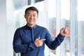 Portrait of happy and successful asian businessman, man smiling and looking at camera pointing with finger towards Royalty Free Stock Photo