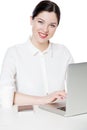 Portrait of happy successful attractive brunette businesswoman in white shirt sitting with laptop, looking with toothy smile Royalty Free Stock Photo