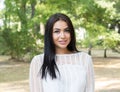 Portrait of happy successful beautiful Indian young woman smiling, looking at camera isolated green trees park background Royalty Free Stock Photo