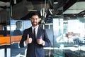 Happy and successful businessman looking at camera and smiling, approvingly showing thumbs up in modern office Royalty Free Stock Photo